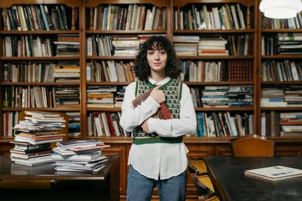 College student standing in front of books and shelves